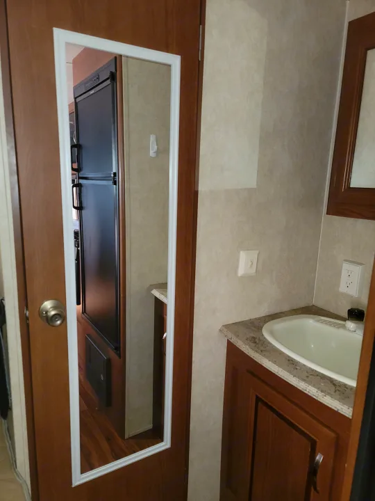 RV rental interior: bathroom sink, counter, and outlets; mirrored door reflects fridge/kitchen setup.. Forest River Salem 2016