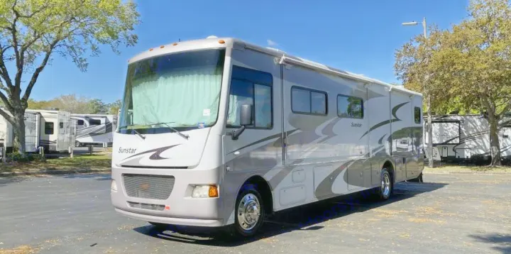Grey & white Sunstar motorhome, ideal for your next rv rental. Parked in a sunny outdoor lot with other RVs.. Itasca Sunstar 2013