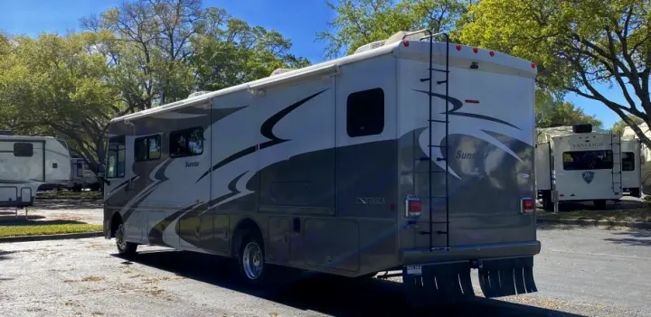 A grey and white Sunstar Itasca motorhome, perfect for rv rental, parked in an outdoor lot with other RVs.. Itasca Sunstar 2013