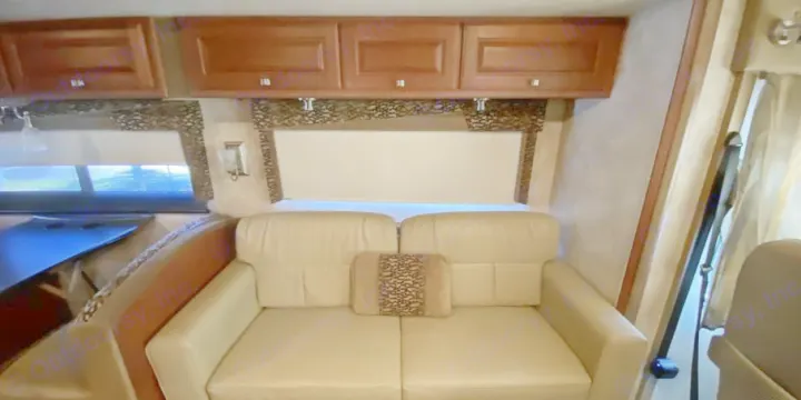 Inside an RV rental: light-colored sofa seating, wood overhead cabinets, and windows with shades.. Itasca Sunstar 2013
