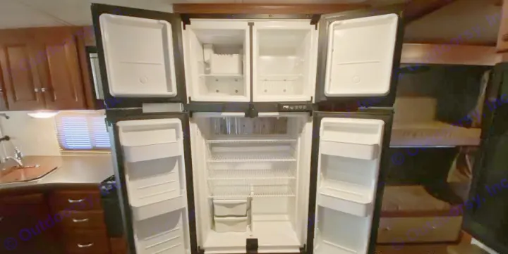 Clean RV rental interior featuring a large open refrigerator, practical kitchen, and built-in bunk beds.. Itasca Sunstar 2013