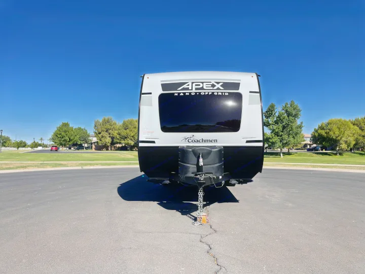 Front view of a white and black Coachmen Apex Nano RV rental, parked on asphalt under a clear blue sky.. Coachmen Apex 2022