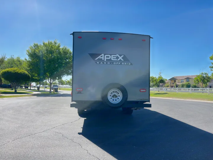 Rear of a grey Apex Nano Off Grid travel trailer, great for RV rental adventures, parked on a sunny day.. Coachmen Apex 2022