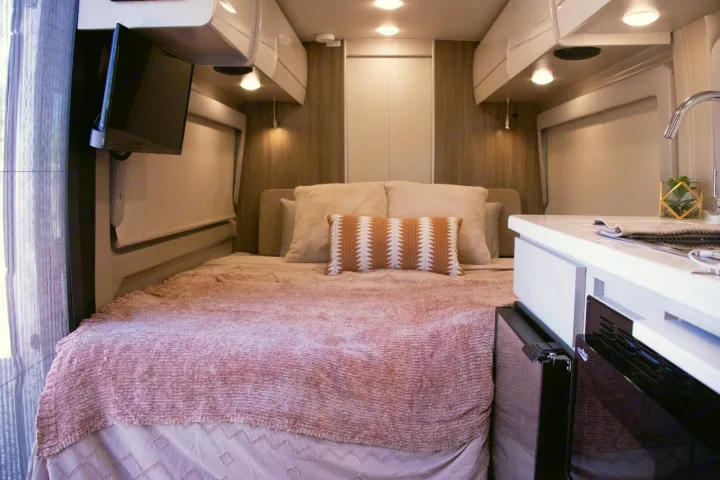 Explore this cozy RV rental interior: comfortable bed, compact kitchen, and TV. Perfect for road trip adventures.. Thor Other 2023