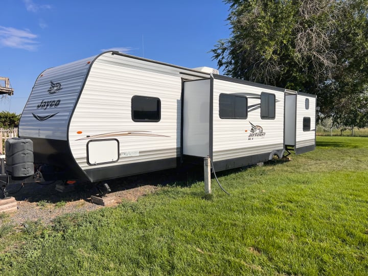 White Jayco Jay Flight travel trailer, perfect for your next RV rental. Parked on grass with slide-out extended.. Jayco Jay Flight 2016