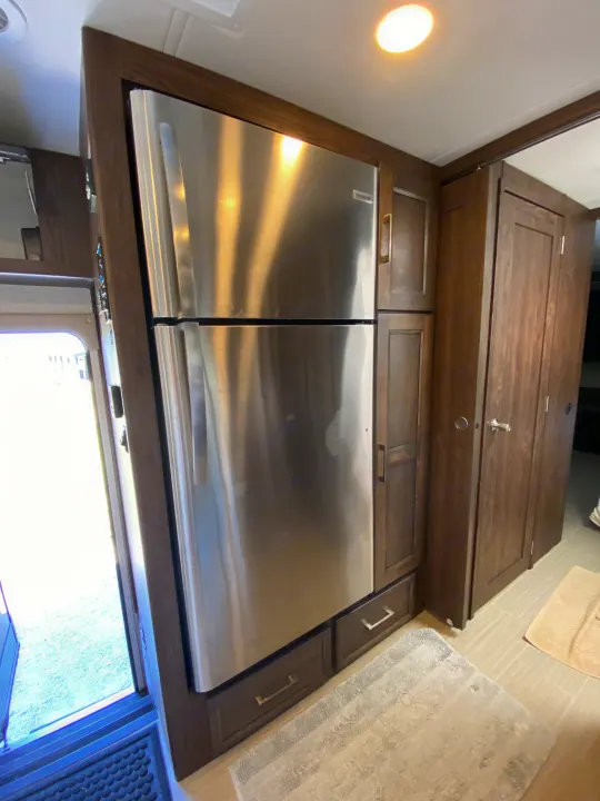 Sleek RV rental kitchen featuring a large stainless steel refrigerator, integrated into rich dark wood cabinetry.. Coachmen Sports Coach 339DS 2019
