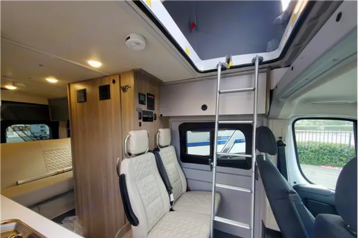 Interior of a compact RV rental, showcasing a bunk bed ladder, comfortable seating, and functional living space for travel.. Winnebago Solis 2022