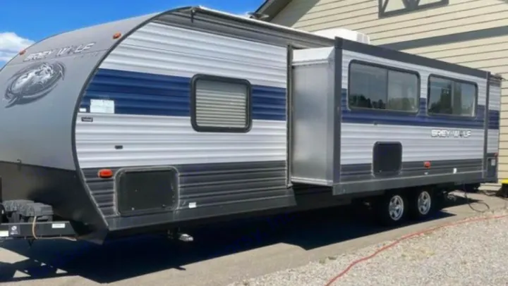 A Grey Wolf RV rental travel trailer with an extended slide-out, parked outdoors on a sunny day.. Forest River Cherokee Grey Wolf 2021