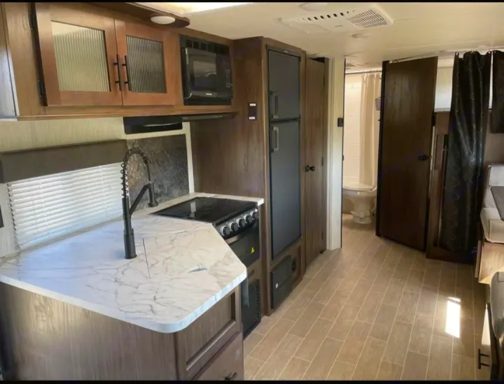 Explore this RV rental's modern interior: a full kitchen with sink, stove, microwave, and a compact bathroom. Your comfy home on wheels.. Forest River Cherokee Grey Wolf 2021