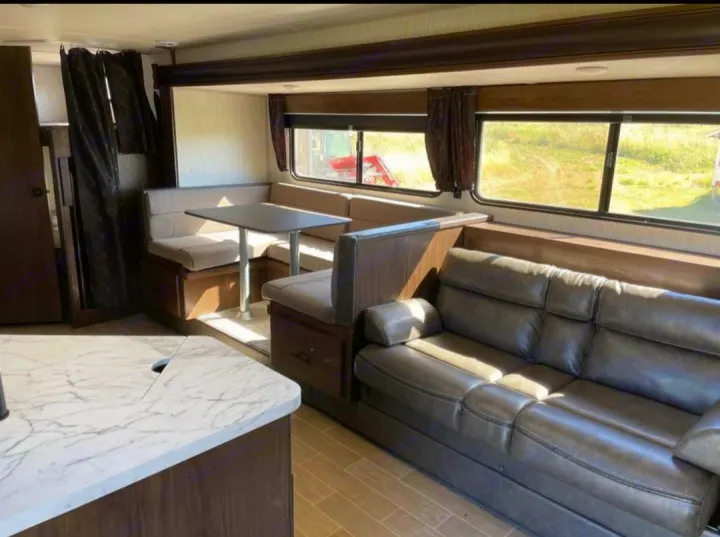 Spacious RV rental living area with a comfortable dinette and plush sofa, ideal for your next camper trip.. Forest River Cherokee Grey Wolf 2021