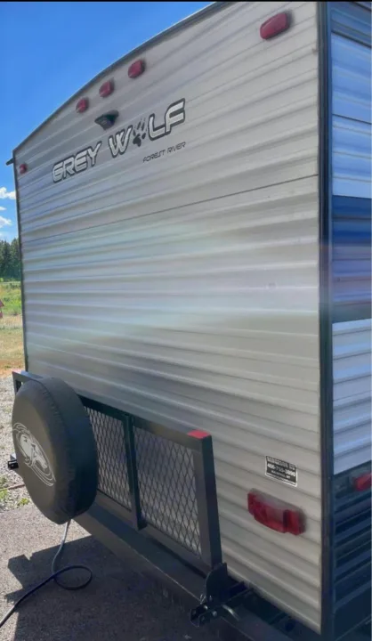 Rear view of a Grey Wolf travel trailer rv rental, showing its spare tire and cargo rack. Ready for adventure.. Forest River Cherokee Grey Wolf 2021