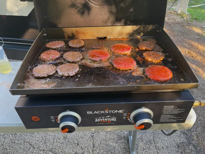Fresh burgers sizzling on a Blackstone griddle, ideal for outdoor cooking during an RV rental trip.. Grand Design Imagine 2400BH 2021