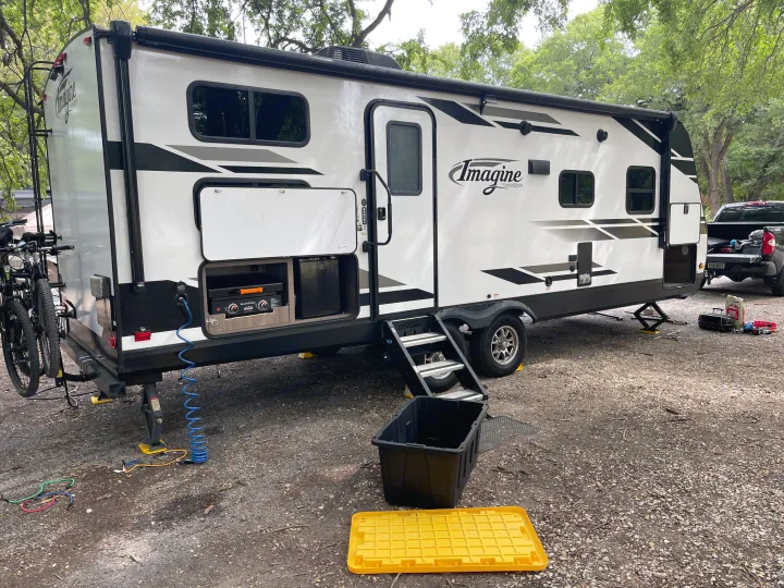Imagine travel trailer RV rental at a campsite. Features an outdoor griddle, mini-fridge, and bike rack.. Grand Design Imagine 2400BH 2021