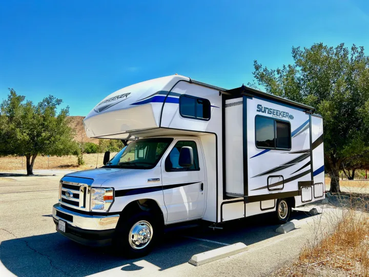 This white Sunseeker Class C RV rental, featuring blue and black decals, is parked outdoors on a sunny day, ready for adventure.. Forest River Sunseeker 2022