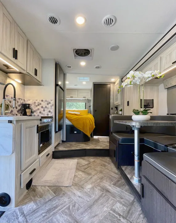 Modern rv rental interior showcasing a bright kitchen, cozy dining booth, and elevated bedroom. All the comforts for travel.. Forest River Sunseeker 2022