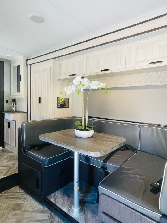 This inviting RV rental interior features a modern dinette with bench seating, table, and kitchenette.. Forest River Sunseeker 2022