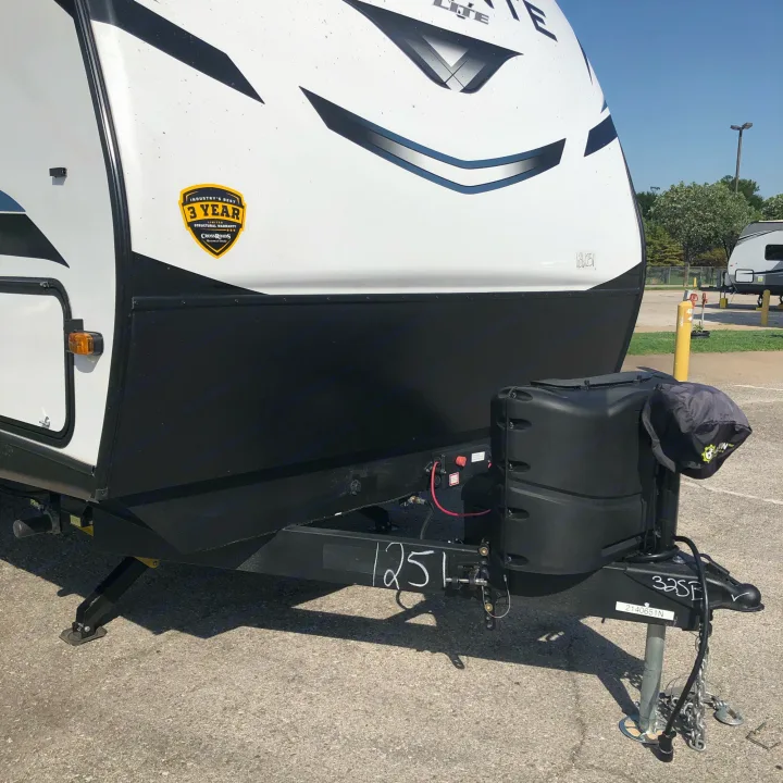 A white travel trailer, ready for rv rental, showing its front, hitch, black propane tank cover, and a 3-year structural warranty.. Crossroads RV Volante 2022