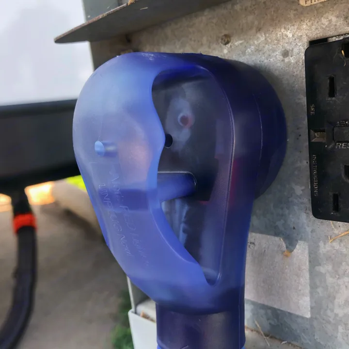 A purple power plug provides an electrical hookup for an RV rental, connected to an outdoor outlet with visible instructions.. Crossroads RV Volante 2022