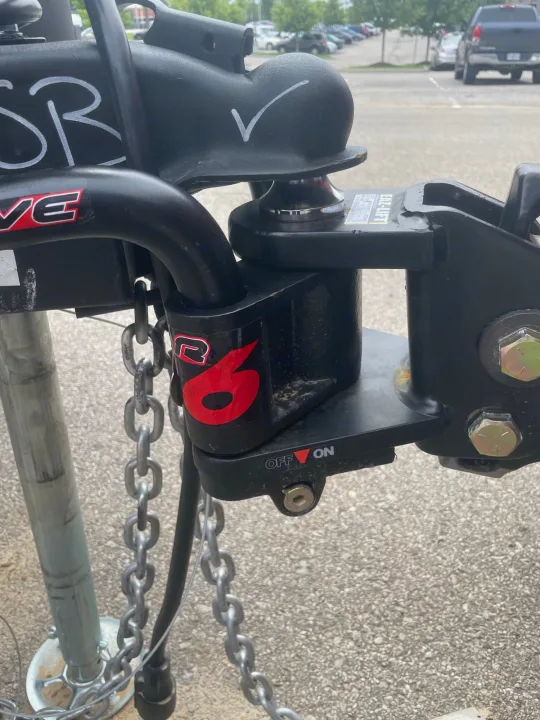 Close-up: RV rental's black EZ-LIFT weight distribution hitch with safety chains, showing ON/OFF control, ready for towing.. Crossroads RV Volante 2022