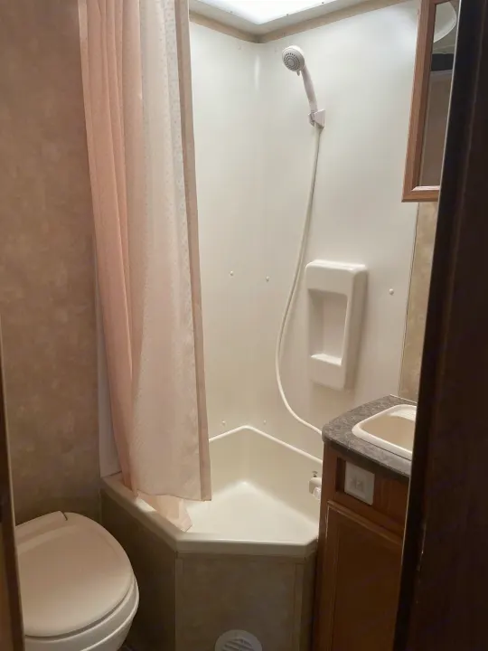 Step inside this RV rental bathroom featuring a corner shower, toilet, and vanity sink for your adventures.. Jayco Jay Feather Exp 2010