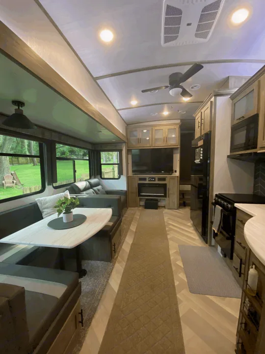 Inside a modern rv rental: spacious living area with dining, TV, and full kitchen, perfect for comfortable travel.. Forest River Hemisphere 2023