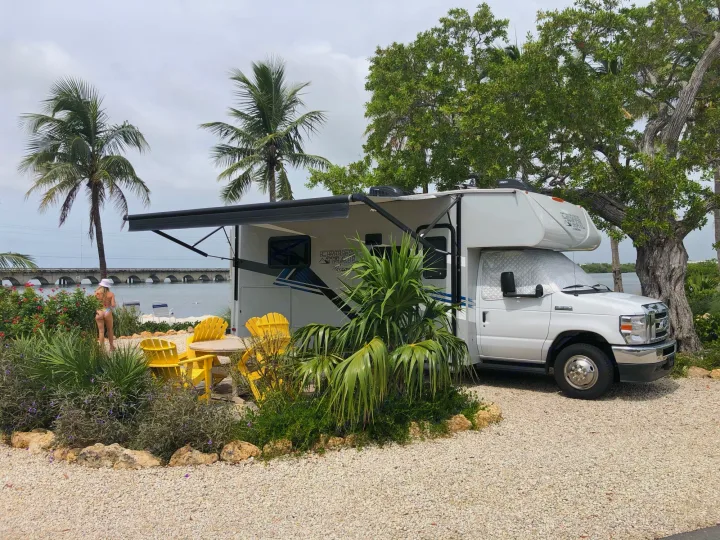 Enjoying a scenic RV rental spot! White motorhome, extended awning, yellow chairs, and ocean views with a bridge.. Forest River Coachmen Cross Trail XL 2022