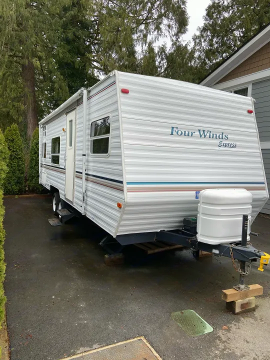 White Four Winds Express travel trailer parked on a driveway, ideal for an RV rental.. Dutchmen Express 2001