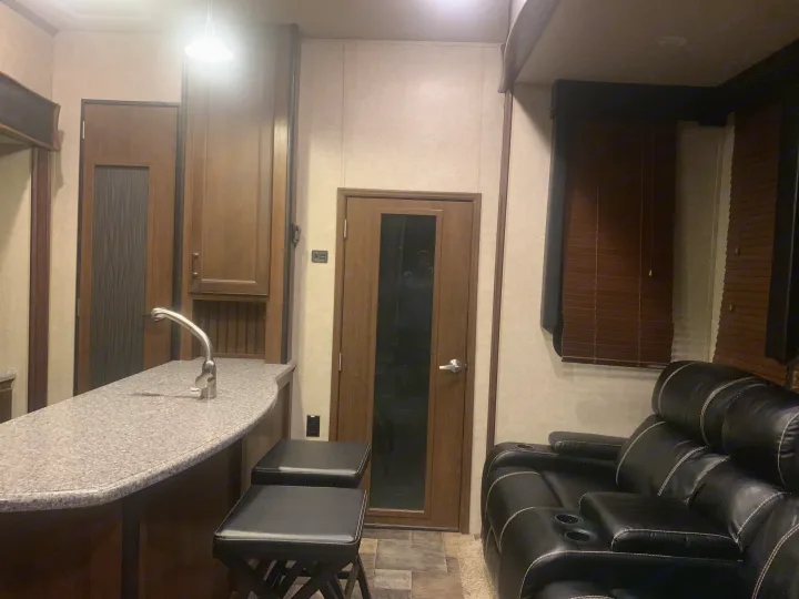 RV rental's inviting interior: kitchen bar with sink, stools, and cozy recliners for comfortable travel.. Keystone Fuzion 2015