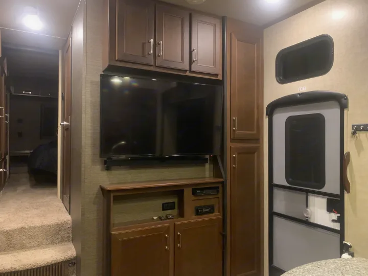 Explore this RV rental's cozy interior: entertainment center, storage, carpeted steps to bedroom, and exit.. Keystone Fuzion 2015