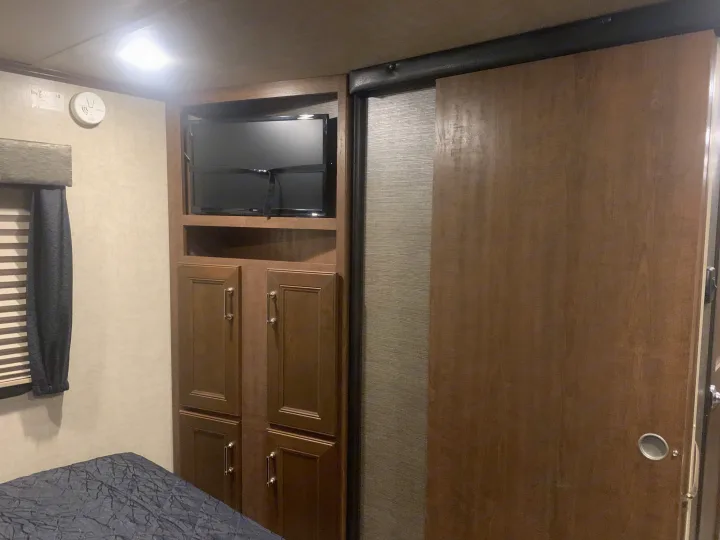 RV rental interior: Bedroom with built-in storage, TV, and a wooden sliding door for efficient space.. Keystone Fuzion 2015