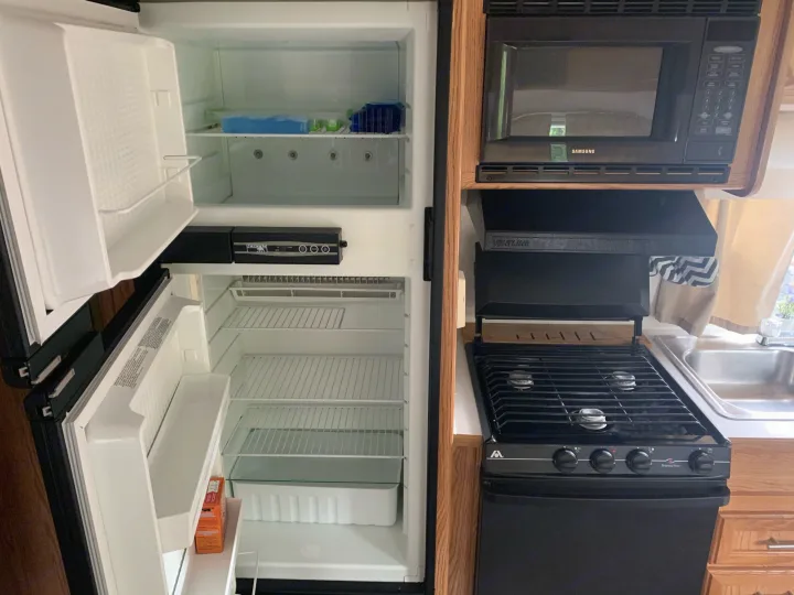 Open Norcold fridge, Samsung microwave, stove, & sink in this RV rental kitchen, ready for your adventure.. Dutchmen Express 2001