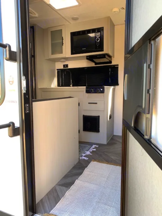 RV rental interior: Bright kitchen/dining area with microwave, stove, sink, and convertible table. Ideal for travel.. Forest River Salem FSX 2022