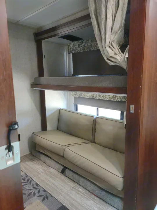RV rental interior: A bunk bed with TV above a light sofa by a window. Ideal for road trips.. Forester LE 2020