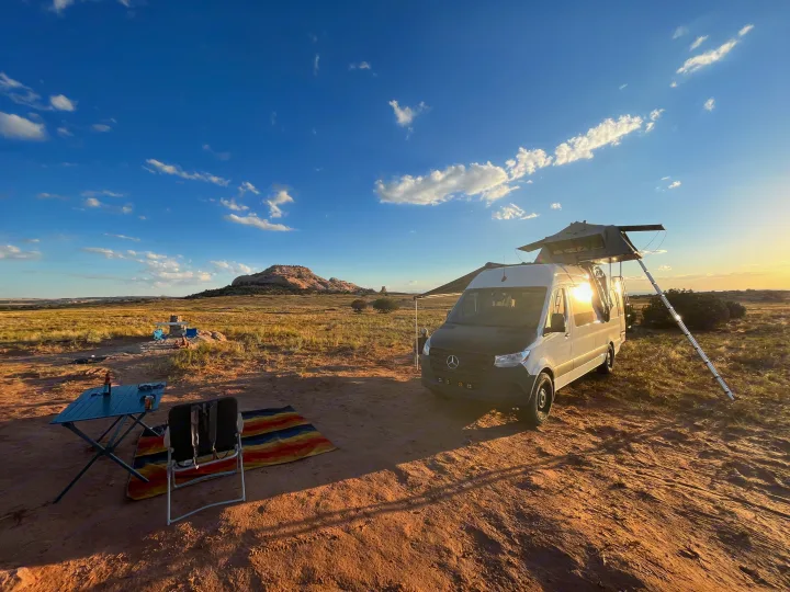RV rental van with rooftop tent, set up for camping in a scenic desert landscape with mountains.. Mercedes-Benz Sprinter 419 LWB High Roof 2022