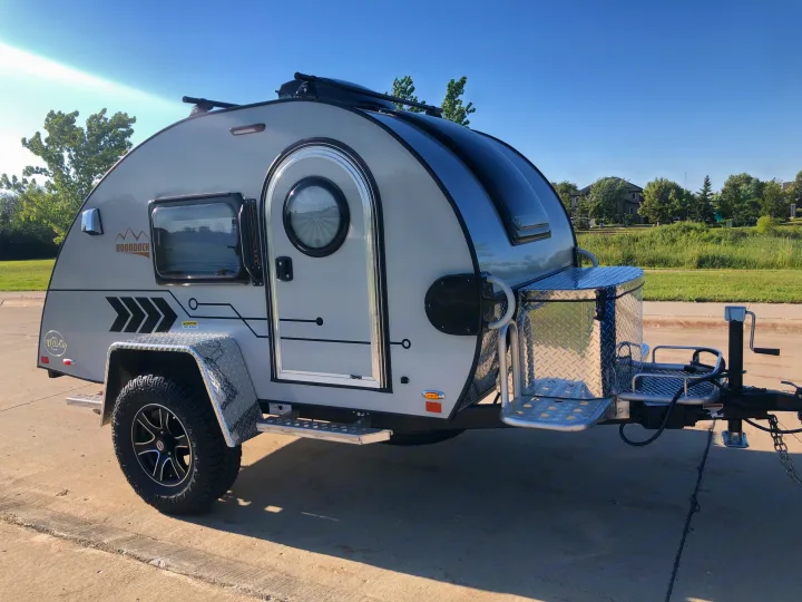 This grey Boondock teardrop travel trailer, a versatile RV rental option, is parked on concrete, ready for adventure.. Nucamp T@G 2022