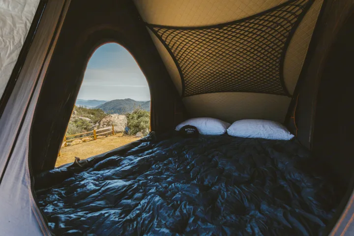 View from a cozy bed inside an RV rental rooftop tent, overlooking scenic mountains, perfect for a camping trip.. Mercedes-Benz Sprinter 2021