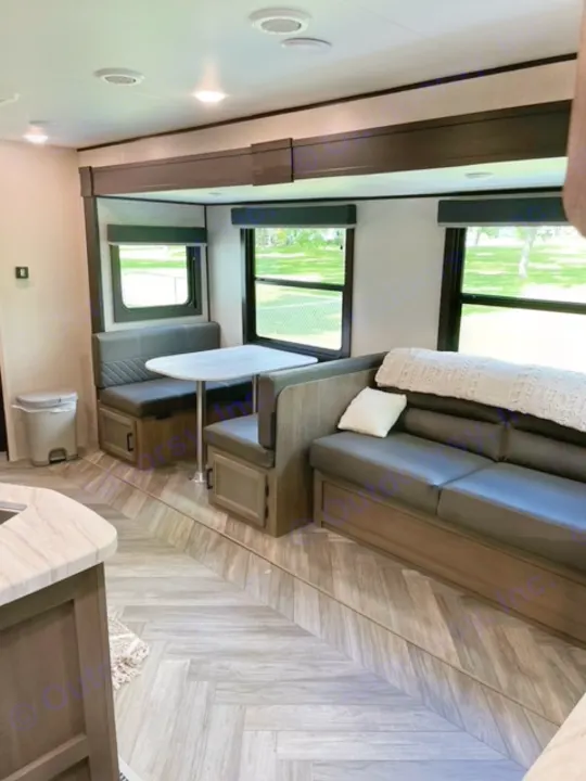 Inside a modern rv rental featuring a cozy dinette, seating area, and stylish wood-look flooring.. Highland Ridge RV Olympia 2022