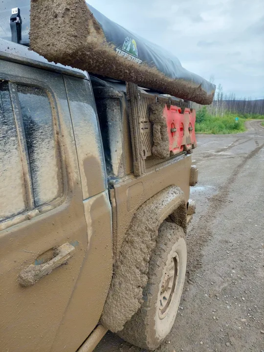 This muddy overland truck, equipped with an awning and recovery boards, looks like a tough **RV rental** for backroads adventures.. Jeep Gladiator 2021