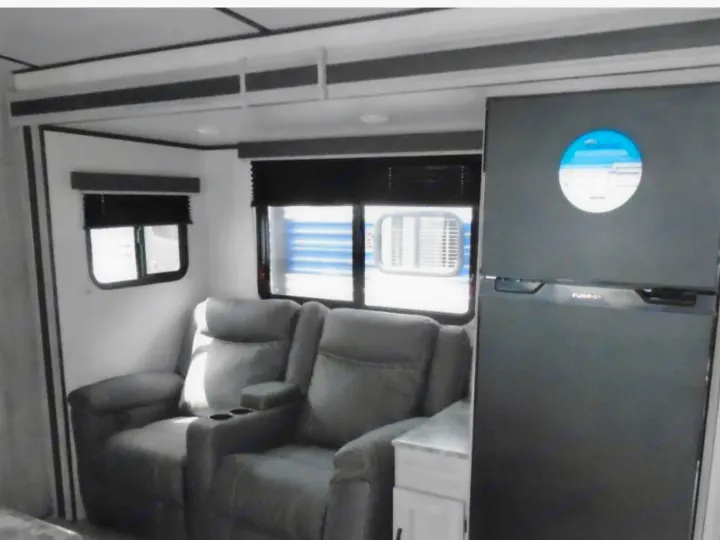 RV rental interior: Cozy living space featuring two recliners, windows, and a black Furrion refrigerator.. Other Other 2022