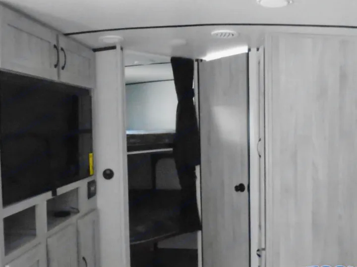 RV rental interior: TV, cabinets on left, hallway to bunk beds, and closet doors on right. Compact living space.. Other Other 2022
