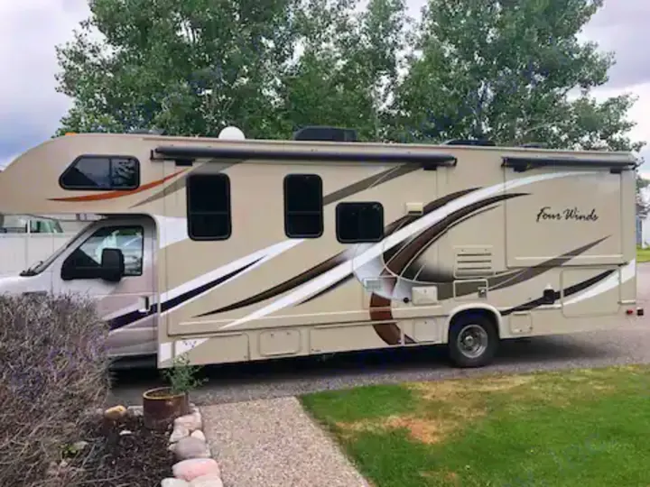 This rv rental: a large beige Four Winds recreational vehicle with brown & white graphics, ready for travel adventures.. Thor Four Winds 2017