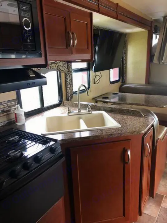Explore the spacious interior of this RV rental, featuring a full kitchen with microwave, stove, sink, and a comfortable dinette.. Thor Four Winds 2017