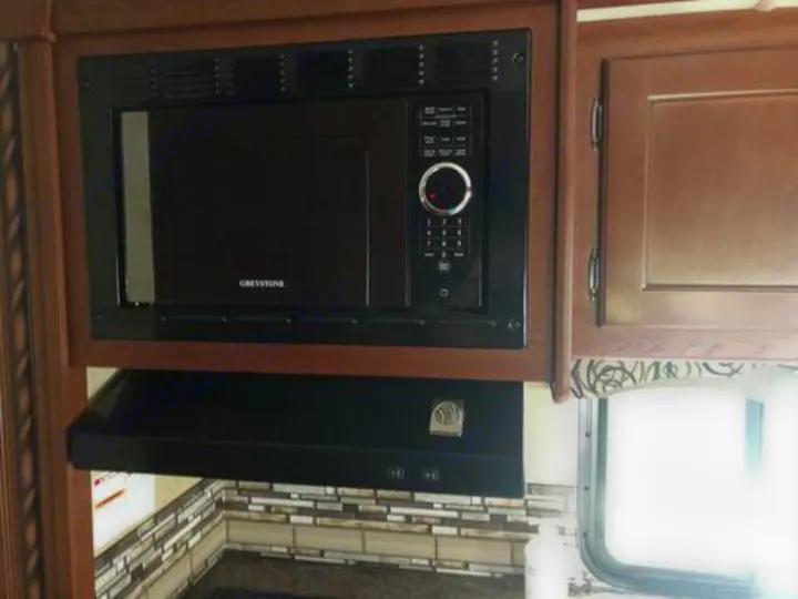 Modern kitchen amenities in this RV rental include a built-in microwave and range hood, enhancing your travel experience.. Thor Four Winds 2017
