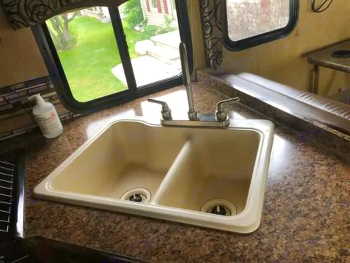 RV rental kitchen featuring a clean double sink, spacious counter, and window view, perfect for travel.. Thor Four Winds 2017