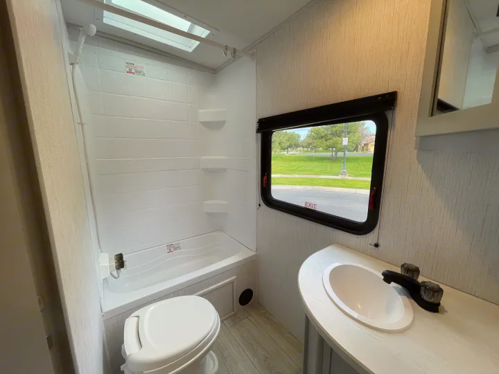 Compact RV rental bathroom featuring a tub/shower combo, toilet, and vanity with a sink. Ideal for travel trailer trips.. Heartland North Trail 2022