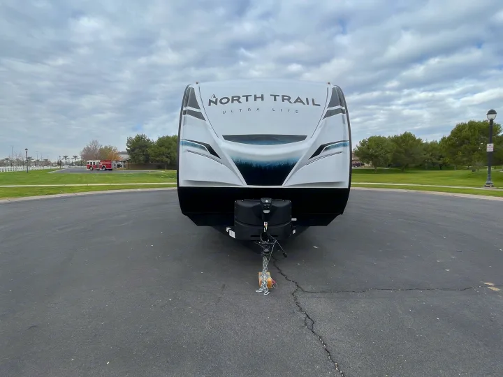 White North Trail Ultra Lite travel trailer, front view, parked on asphalt. Ideal for an RV rental adventure.. Heartland North Trail 2022
