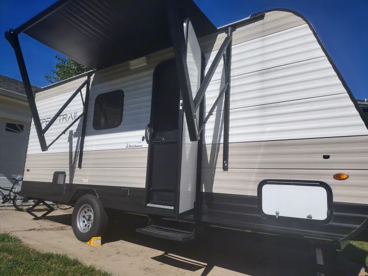 This RV rental, a Dutchmen Apex Trail travel trailer with its awning extended, is parked outdoors, ready for adventure.. Dutchmen 17BH 2021