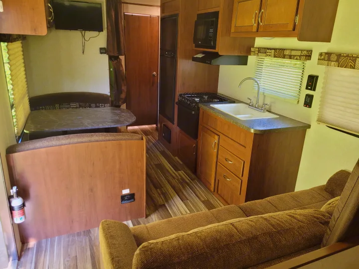 RV rental interior featuring a full kitchen, dining booth, entertainment area with TV, and cozy couch seating.. Jayco Jay Flight SLX 2017