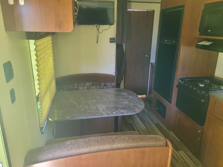 This RV rental offers a comfortable interior with a dinette, full kitchen including stove and fridge, and a mounted TV.. Jayco Jay Flight SLX 2017