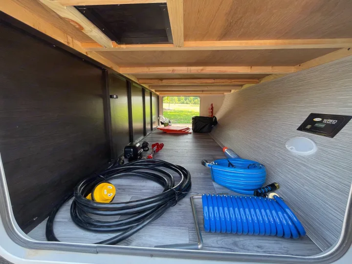RV rental pass-through storage with essential camping utilities: power cord, water hoses, and solar wiring.. Starcraft Super Lite 2022